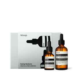Two amber Aesop dropper bottles of different sizes stand in front of a silver-grey box illustrated with black bottle silhouettes.